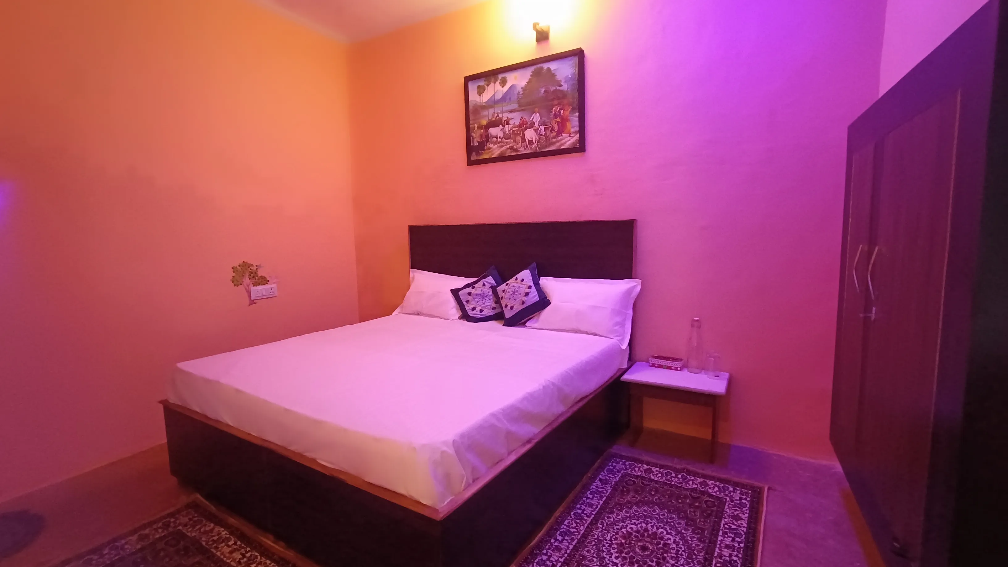 Double bed, bedside table and wall art in the standard room.