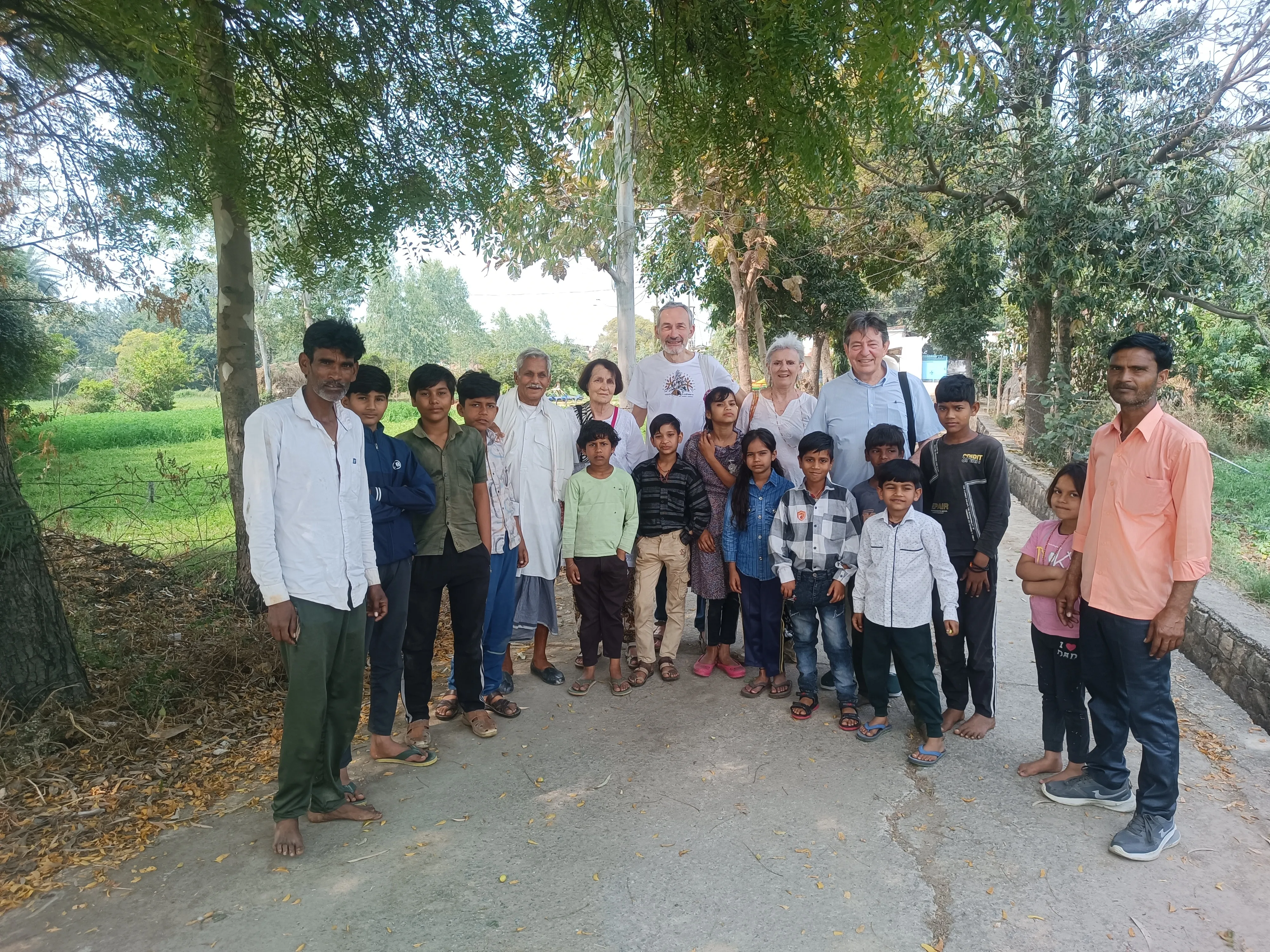 Residents and visitors gather beneath trees along a village lane in Khairwaya.